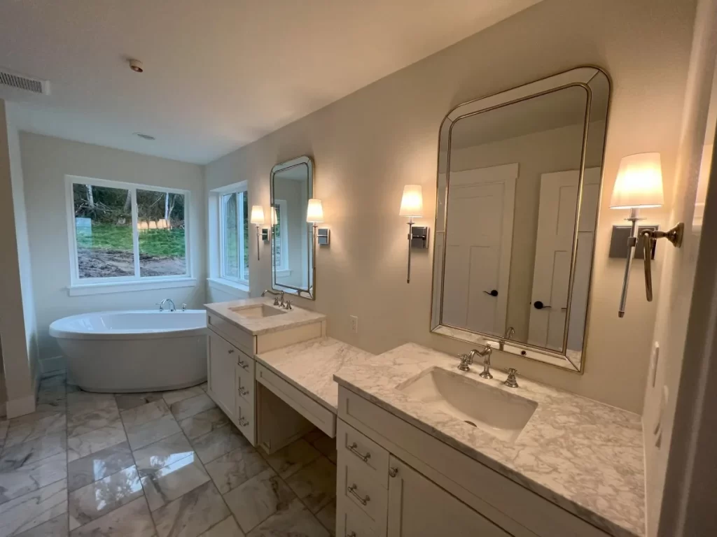 A bathroom with two sinks, a tub and two mirrors where Mauro Electric installed the lights and wiring.