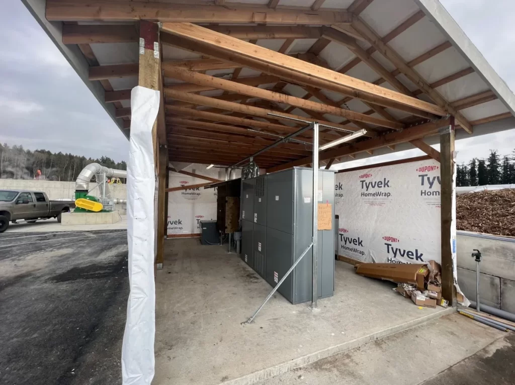 A building under construction with a covered area and a truck parked in the background.